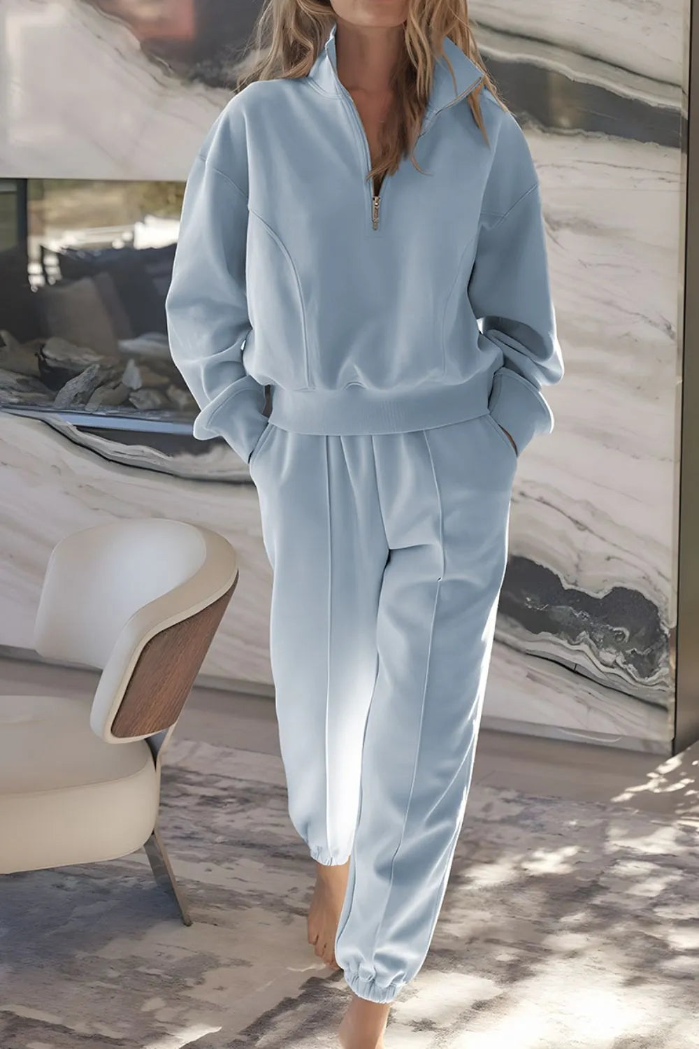 Light blue tracksuit worn by a person in a room with a marble wall.