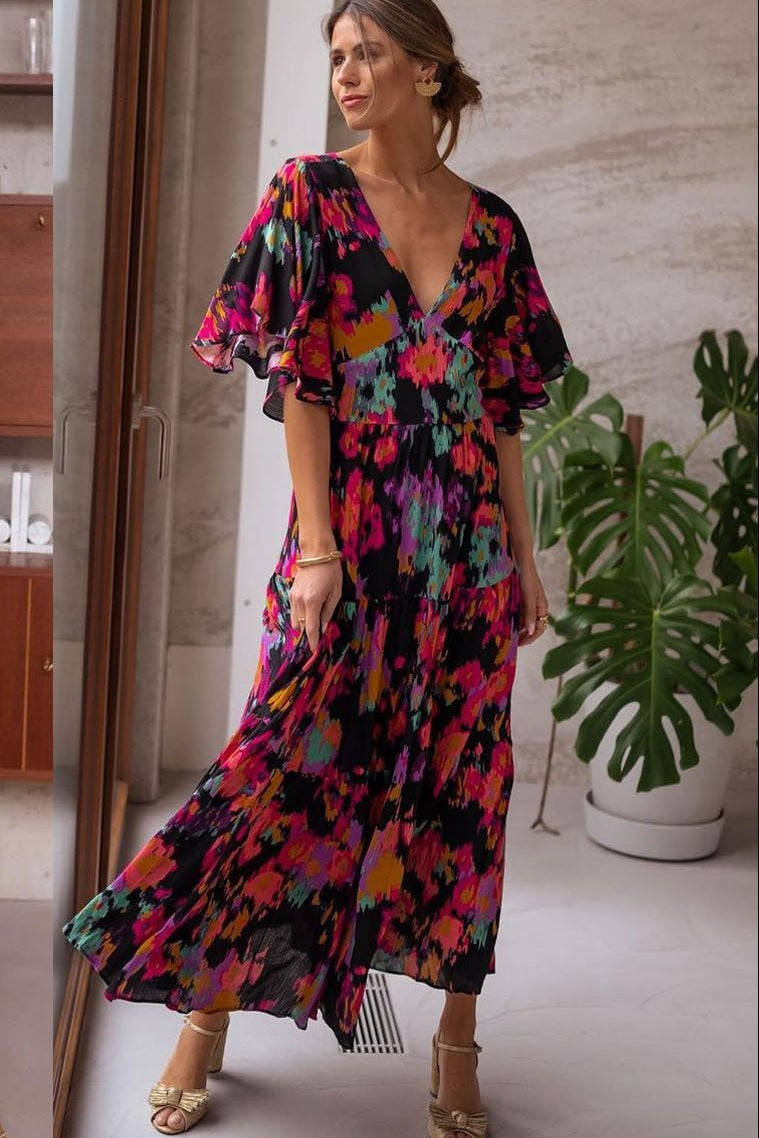 Woman wearing a colorful floral dress in a room with a mirror.