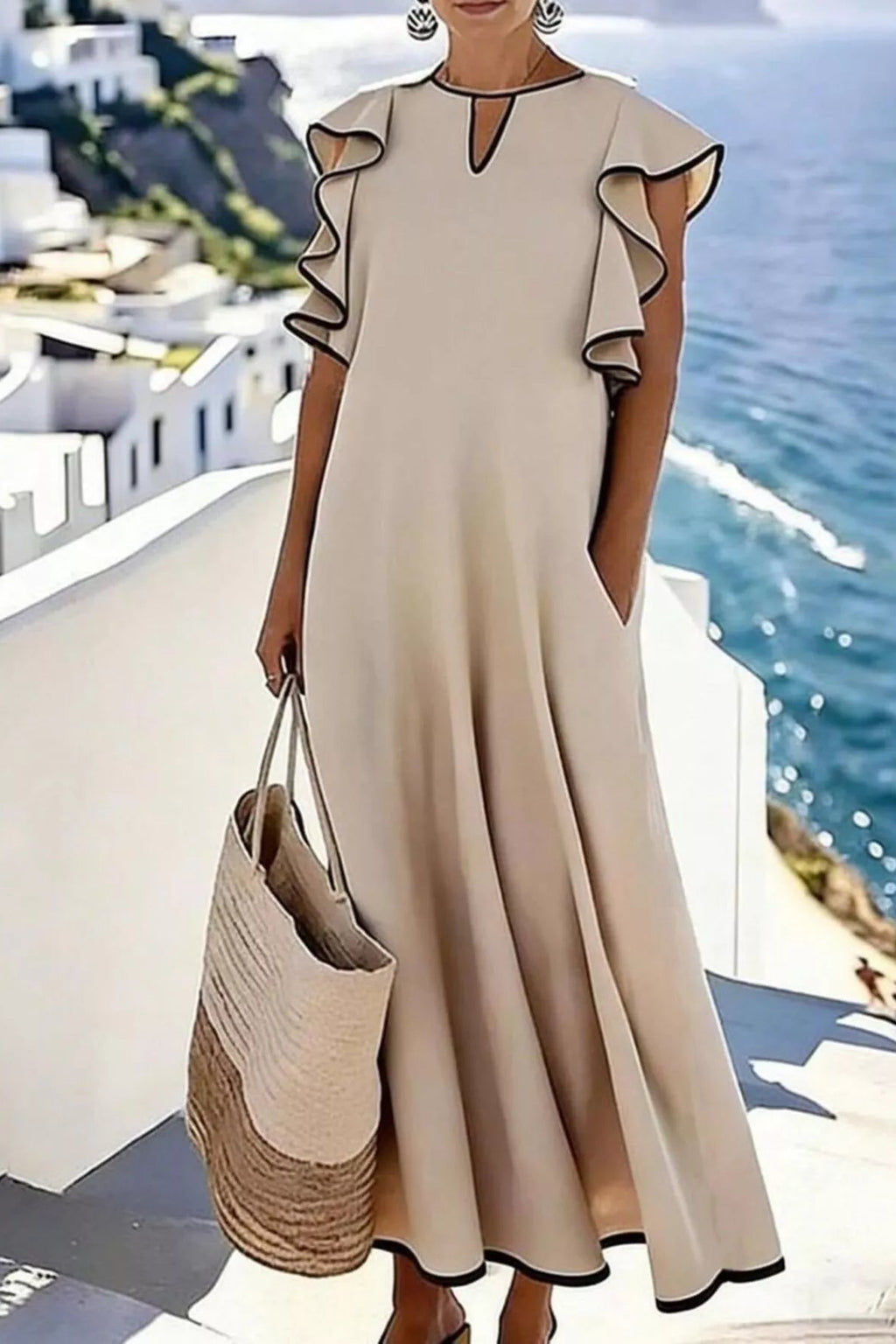 Woman in a beige dress with ruffled sleeves standing on a rooftop with ocean view