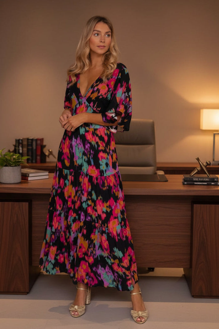 Woman in a colorful floral dress standing in an office setting.