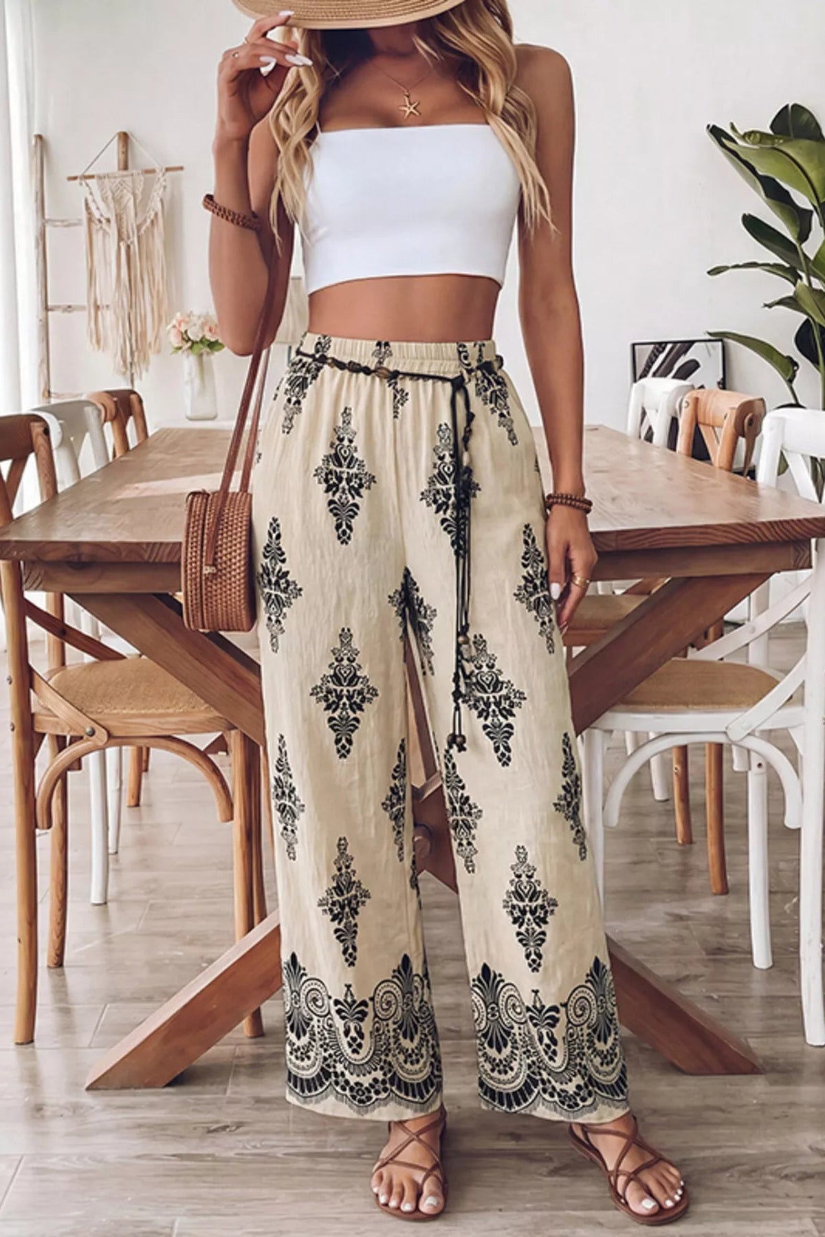 Woman in a white top and patterned pants standing in a dining room.