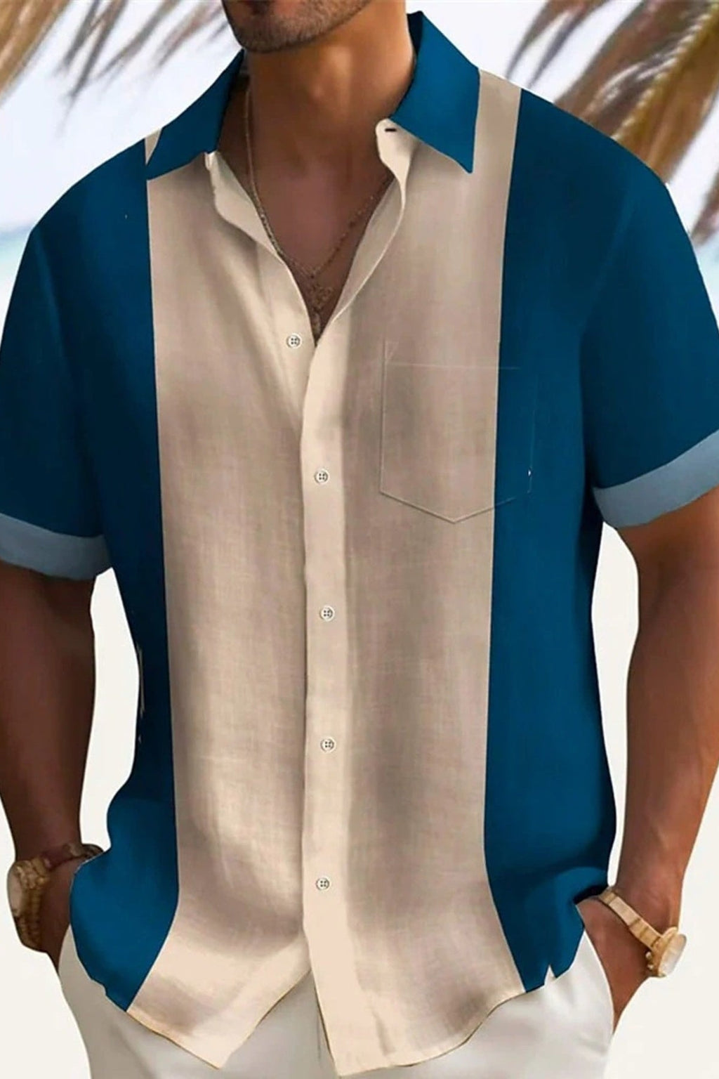 Man wearing a blue and beige button-up shirt with a blurred beach background