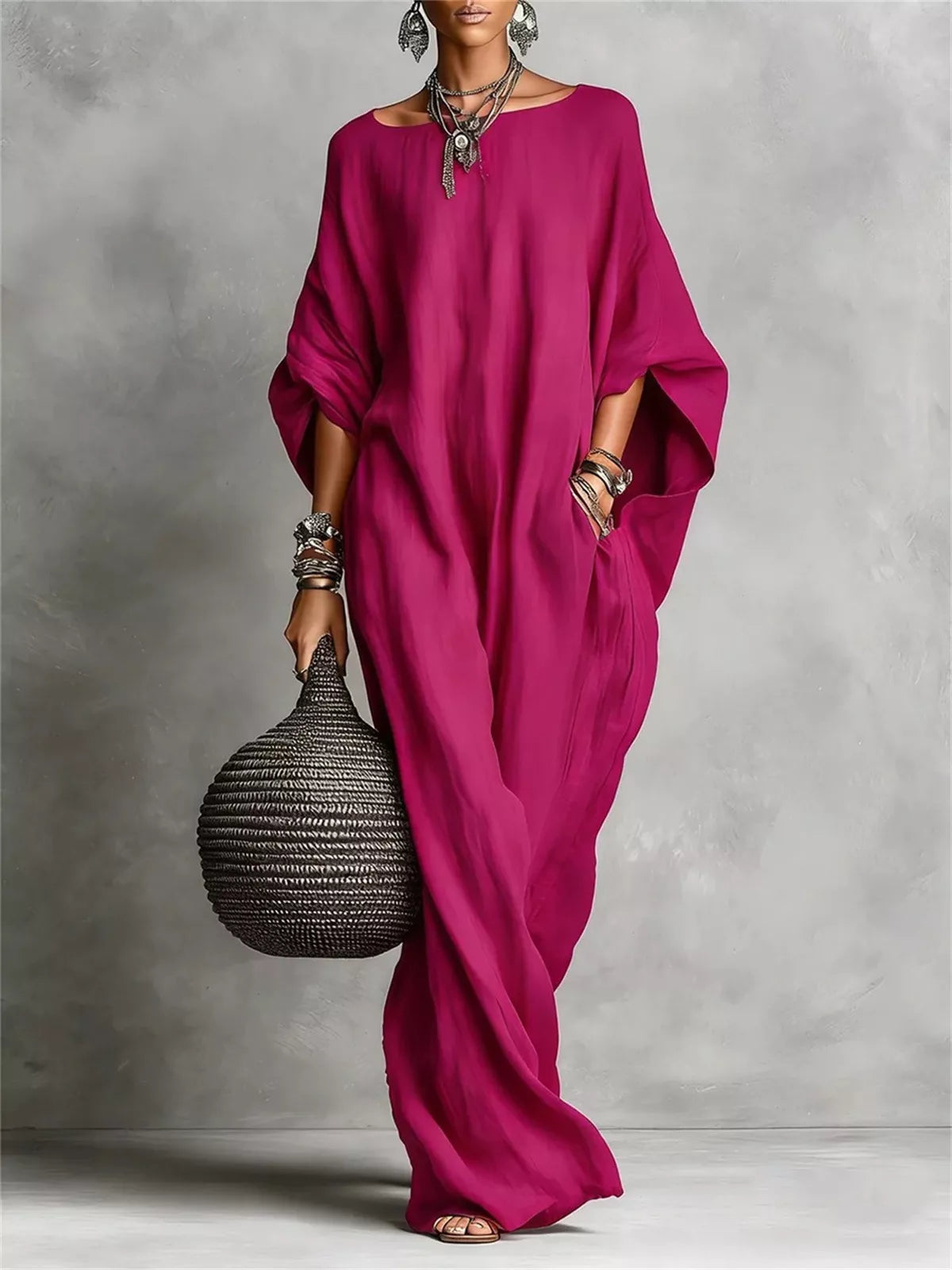 Person wearing a magenta dress holding a textured black bag against a gray background