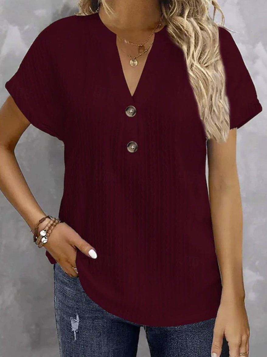 A woman wearing a short-sleeve ribbed knit top in deep burgundy with a V-neck and three front buttons, paired with blue jeans.
