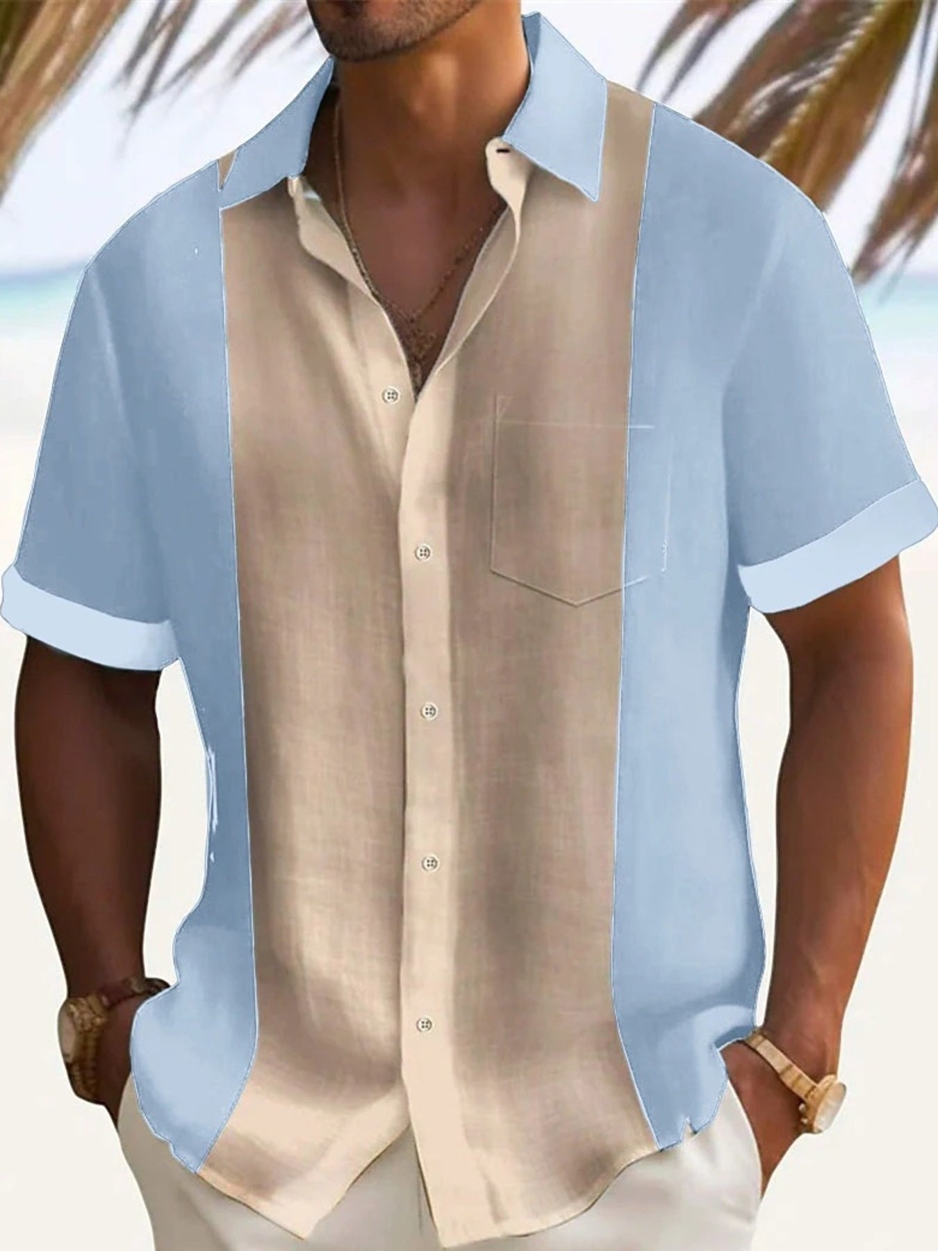 Man wearing a light blue and beige button-up shirt with blurred beach background