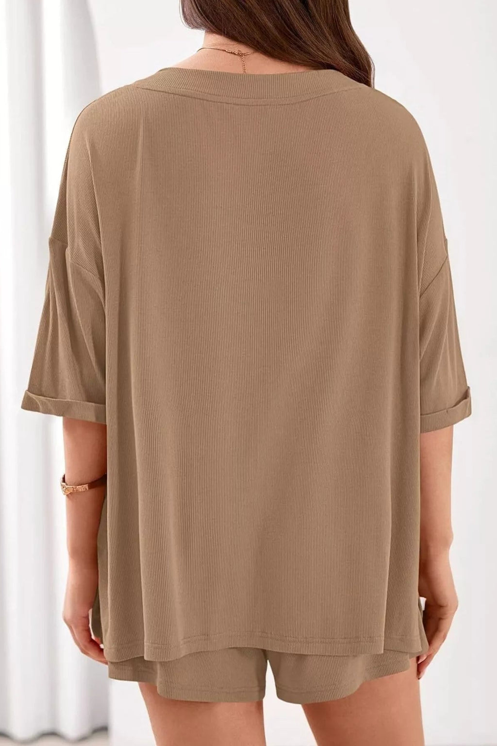 Person wearing a brown oversized t-shirt and shorts set on a white background