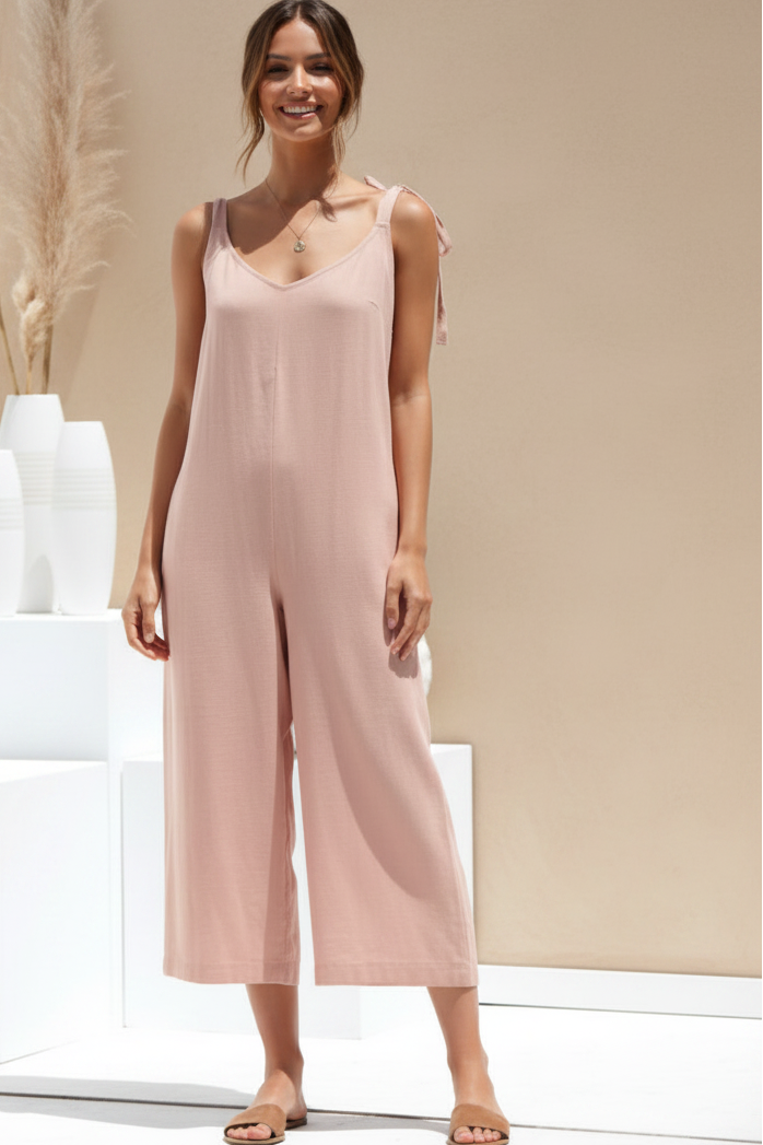 Woman wearing a pink jumpsuit standing against a neutral background