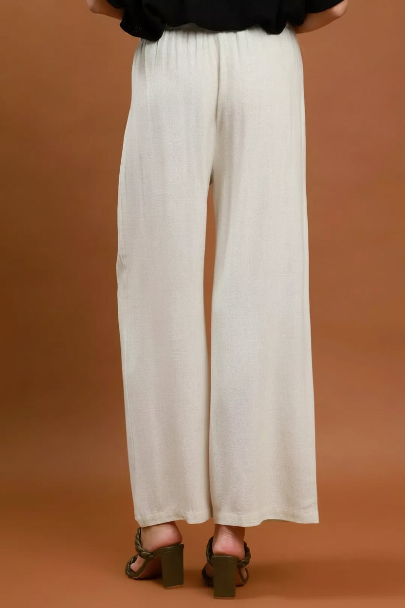 White wide-leg pants worn by a person on a brown background